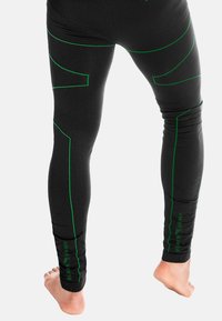 Schwarze Sportleggings mit grünen Akzentnähten, einer figurnahen Passform und strukturiertem Material, mit einem sichtbaren Logo am Unterschenkel.