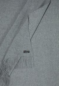 Écharpe en laine grise aux bords frangés, comportant une petite étiquette noire avec le nom de la marque "FRAAS". Texture douce et design uni.