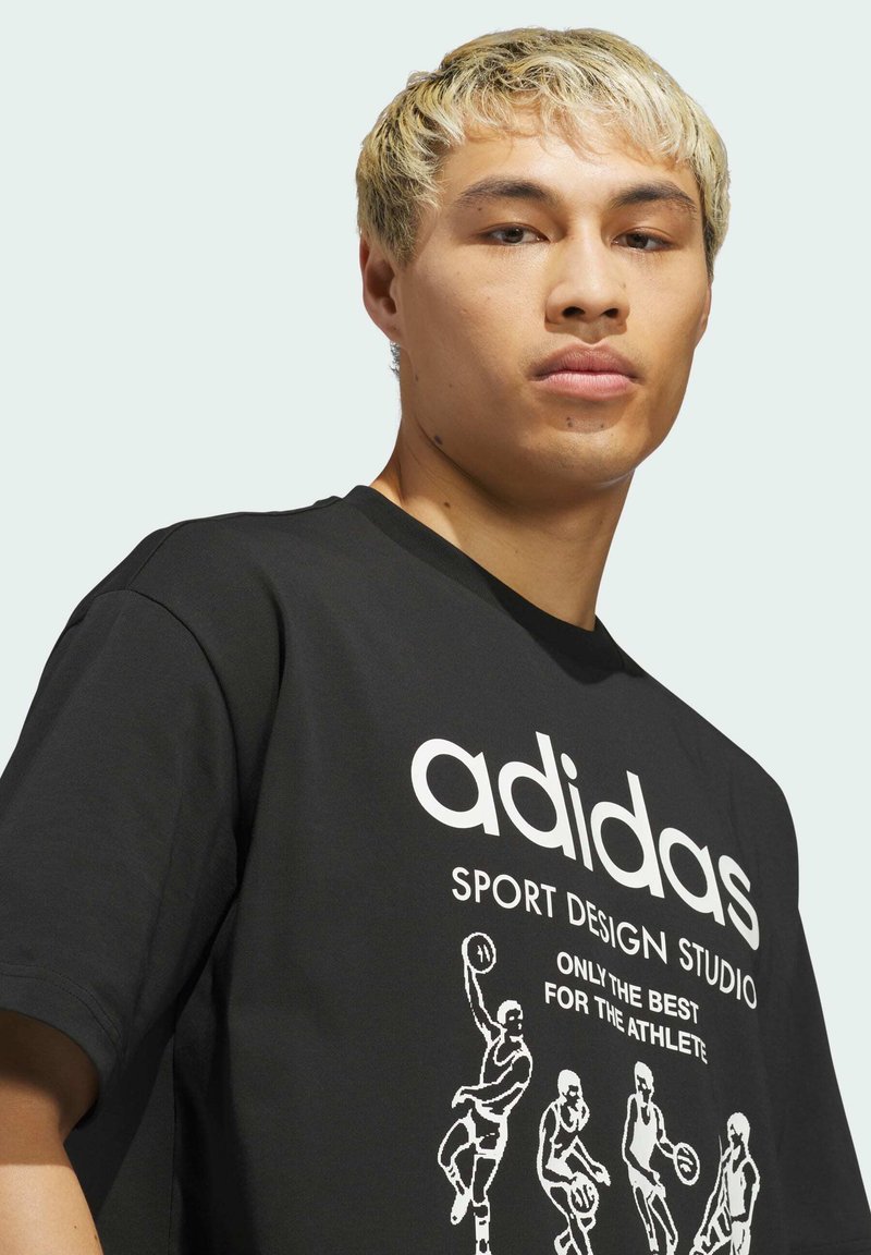 Black cotton t-shirt featuring white "adidas" logo and graphic of basketball players in various poses. Crew neck and short sleeves.