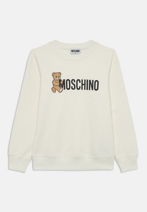 Felpa color crema chiaro realizzata in morbido tessuto, con un orso cartone e la scritta "MOSCHINO" stampata in bold nero. Maniche lunghe con polsini a costine.