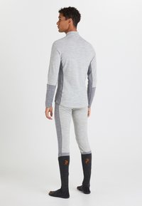Maglietta a maniche lunghe grigia con fori per il pollice abbinata a pantaloni attillati. Tessuto simile al pile, con accenti grigi scuri a contrasto e calze fino al ginocchio.