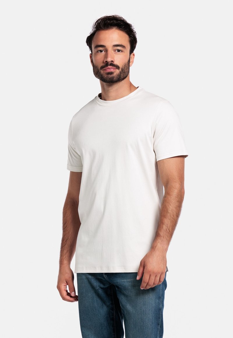 Weißes Baumwoll-T-Shirt mit kurzen Ärmeln und rundem Halsausschnitt. Der Stoff ist glatt, mit subtilen Nähten und einem lockeren Schnitt. Kombiniert mit blauen Jeans.