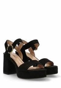 Sandalias de tacón alto de ante negro con un tacón ancho, punta abierta y correas entrelazadas que presentan un detalle circular en dorado.