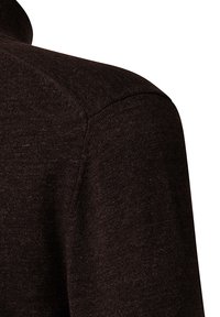 Primo piano di un tessuto di maglione lavorato a maglia marrone scuro che mostra i dettagli delle cuciture sulla spalla e sulla parte superiore della manica.