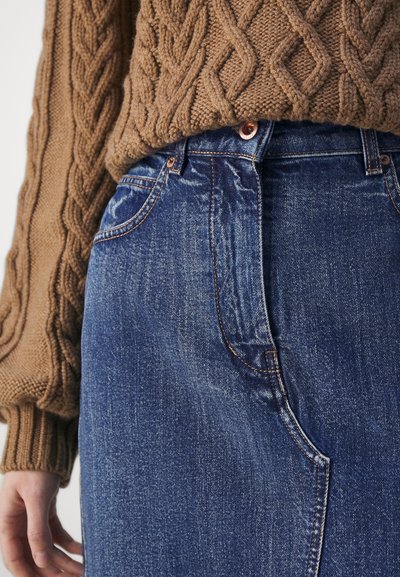 Brun kabelstrikket genser kombinert med blå denimskjørt; har høy midje, kobberknapper og subtile falmingseffekter.