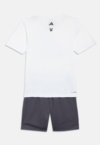 Biele tričko s krátkym rukávom s čiernymi logami Adidas a Minecraft na chrbte, v kombinácii s tmavosivými šortkami.