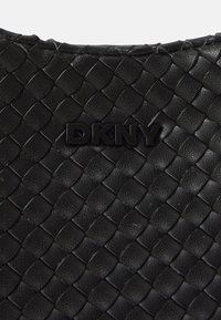 Borsa nera in pelle intrecciata con una finitura testurizzata. Presenta un logo DKNY in rilievo di colore nero lucido. Design compatto che mette in risalto l'artigianato.