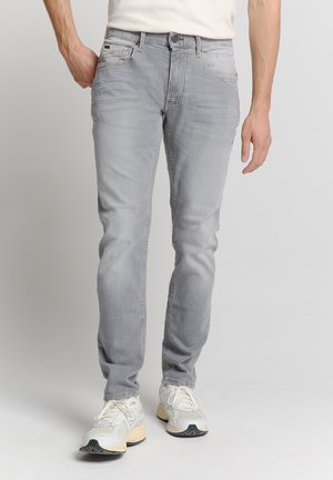 Lichtgrijze slim-fit jeans met een subtiele vervaagde textuur en een vijfzakkenontwerp, gecombineerd met witte sneakers.