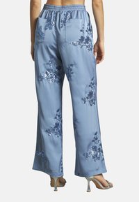 Lichtblauwe satijnen broek met brede pijpen, versierd met bloemenborduursels van sequins en een elastische tailleband, met achterzakken en een relaxte pasvorm.