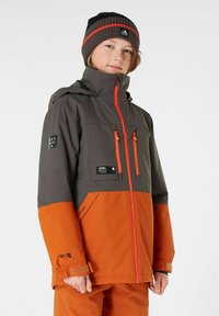 Wasserabweisende Jacke mit grauem Oberteil und orangenem Unterteil, ausgestattet mit Reißverschlusstaschen, verstellbaren Manschetten und einem hohen Kragen.