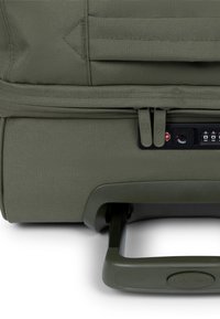 Valise de voyage vert olive avec une surface en tissu texturé, double fermeture éclair, serrure à code et poignée rétractable pour un transport facile.