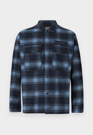 Camicia a maniche lunghe con bottoni, in fantasia a quadri blu e nera, due tasche frontali con bottoni sul petto e una piccola etichetta "Replay" sulla tasca sinistra.