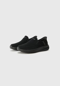 Black slip-on shoes made of mesh fabric with a textured upper, rubber sole, and elastic side panels for easy wear. Minimalistic design.