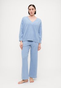 Light blue loungewear set featuring a v-neck oversized sweater and wide-leg pants made of soft textured fabric.