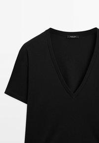 Czarny t-shirt z dekoltem w serek, wykonany z gładkiej bawełny, z krótkimi rękawami i starannym wykończeniem dekoltu oraz mankietów.