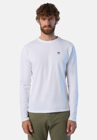 Camicia bianca di cotone a maniche lunghe con scollatura tonda, caratterizzata da un logo circolare blu sul petto e maniche aderenti.