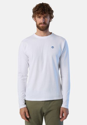 Camicia bianca di cotone a maniche lunghe con scollatura tonda, caratterizzata da un logo circolare blu sul petto e maniche aderenti.