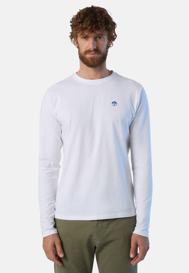 Camicia bianca di cotone a maniche lunghe con scollatura tonda, caratterizzata da un logo circolare blu sul petto e maniche aderenti.