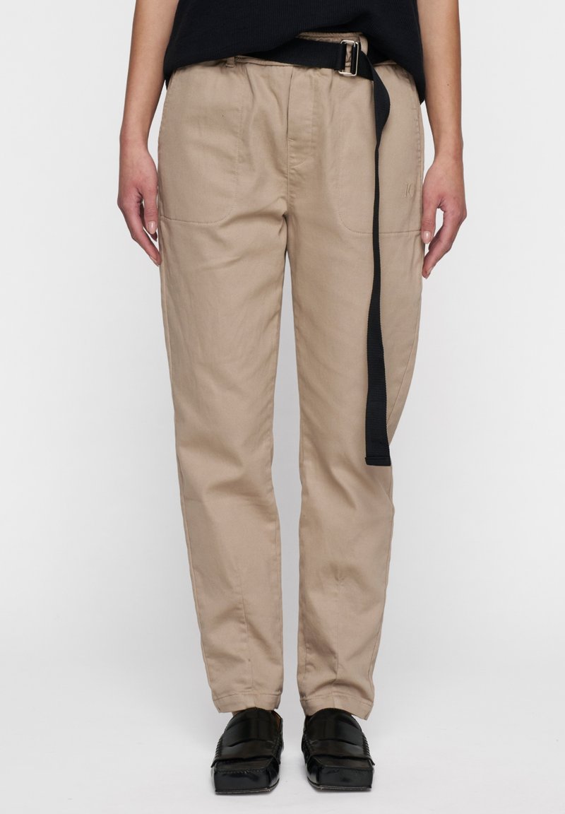 Beige, lichtgewicht katoenen broek met een ontspannen pasvorm, voorzien van een zwarte riemdetail en zijzakken. Gladde textuur en gestikte accenten.