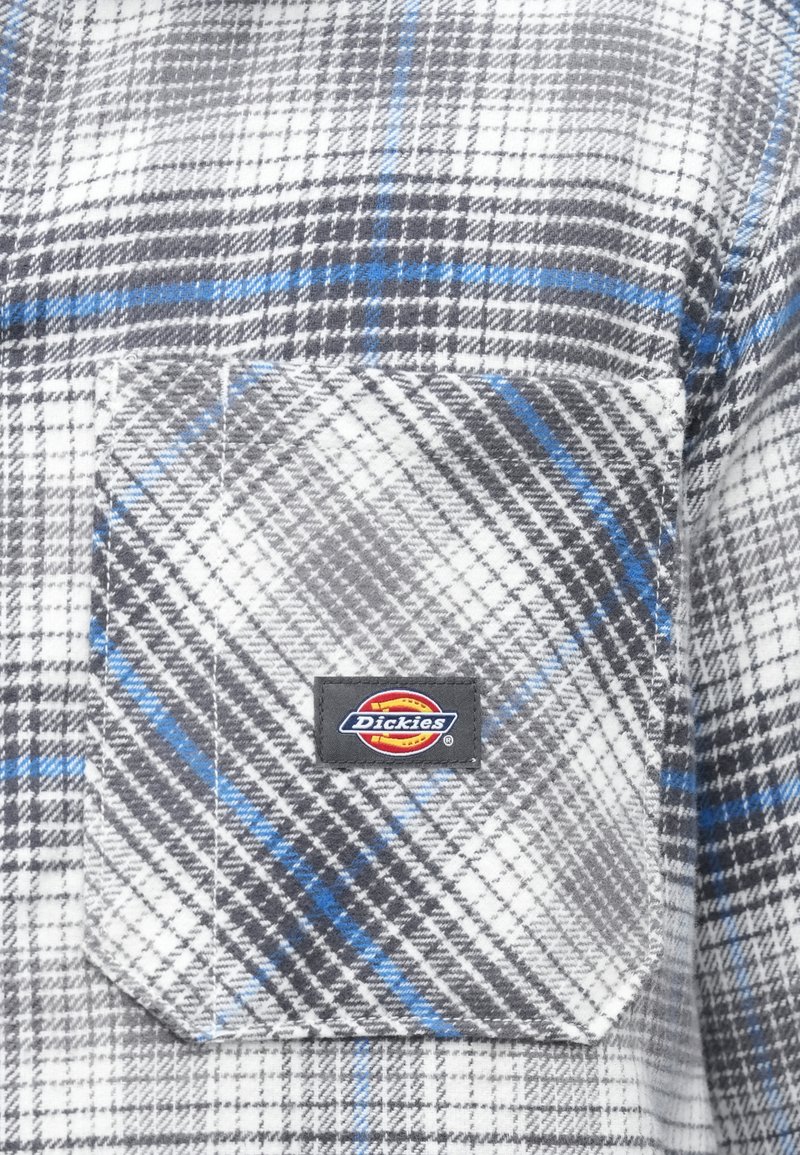 Grau-weiß kariertes Flanellhemd mit blauen Akzenten, verfügt über eine Brusttasche und einen schwarzen Dickies-Logo-Patch. Weicher, strukturierter Stoff.