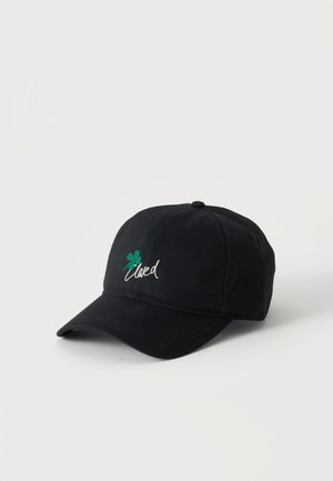 Schwarze Baseballkappe mit grünem vierblättrigem Kleeblatt und weißem Kursivschriftzug vorne, dargestellt auf einfachem hellen Hintergrund.