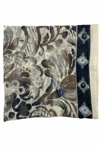 Coussin en tissu à motif floral avec des nuances de brun et de beige, présentant une bande d'accent bleu foncé avec des éléments décoratifs et une texture.