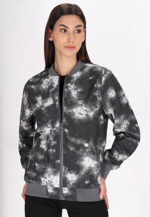 Giacca bomber grigia con un motivo astratto bianco e nero, polsini e orlo a coste, e chiusura frontale con zip. Texture del tessuto liscia.