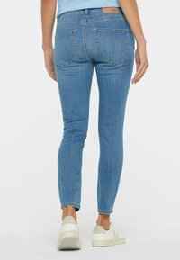 Skinny jeans in light blue denim with a smooth texture, featuring a mid-rise waist, five-pocket design, and subtle stitch detailing.