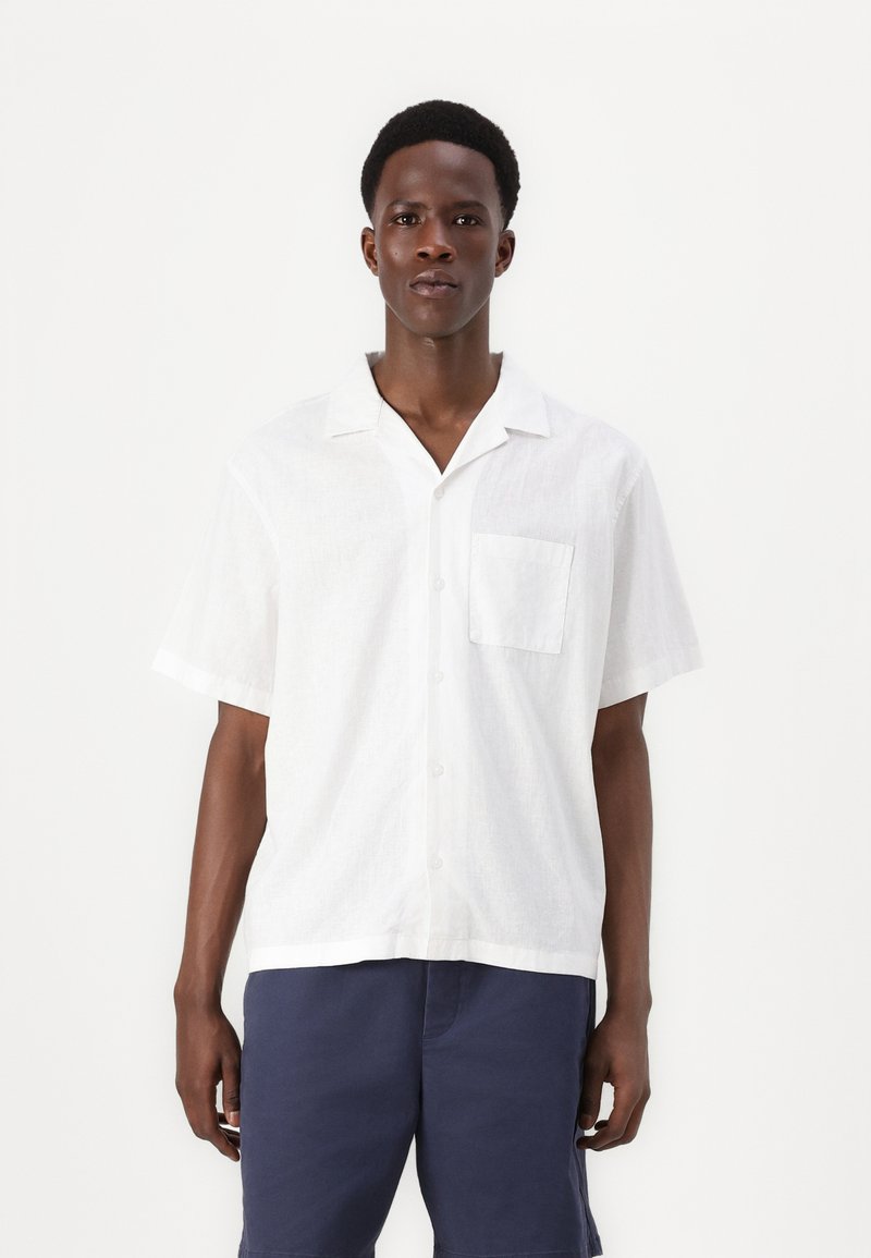 White short-sleeved button-up shirt made of lightweight fabric, featuring a pocket and a relaxed fit. Smooth texture and classic collar design.