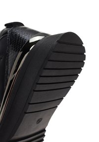 Sneaker nera con tomaia testurizzata e un accento metallico lucido, suola in gomma resistente con design a scanalature e logo.