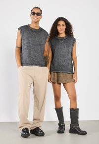 Gray, short-sleeve, textured T-shirts paired with beige pants and a plaid skirt. Footwear includes chunky black boots and loafers.