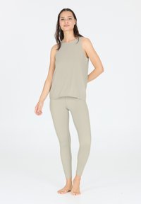 Top senza maniche di un verde oliva chiaro abbinato a leggings aderenti coordinati. Tessuto liscio e elasticizzato con una vestibilità comoda e cuciture minime.