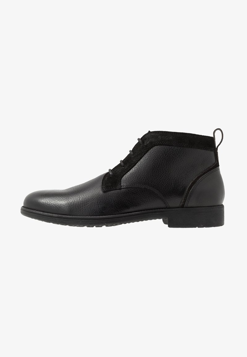 Bottes courtes en cuir noir à finition lisse, avec des accents en suède, un design à lacets et une semelle basse en caoutchouc. Forme compacte avec un bout rond.