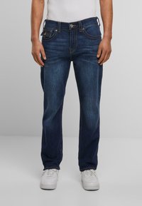 Donkerblauwe denim jeans met een rechte pasvorm, voorzien van een klassieke vijf-pocket ontwerpelementen, stikselaccenten en een knoopsluiting bij de taille.