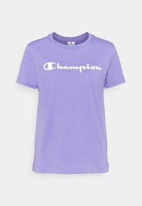 Lila bomullströja med korta ärmar, rund halsringning och en vit "Champion"-logotyp tryckt över bröstet. Slät textur.