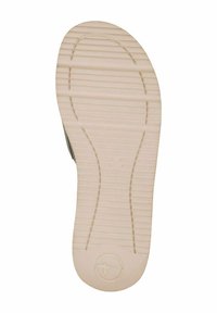 Semelle de chaussure en caoutchouc beige texturé, avec des rainures horizontales pour l'adhérence et un logo circulaire au niveau du talon.