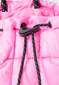 Rožinė pūkinė medžiaga su siuvinėtais segmentais, turinti juodas virves ir reguliatorių su užtrauktuku, skirtu susitraukti. Lygus, lengvas tekstūra.