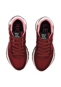 Une paire de chaussures de course bordeaux et roses avec le texte "LES FILLES COURENT PLUS VITE" sur les étiquettes de langue noires et "DROITE" et "GAUCHE" à l'intérieur des semelles.