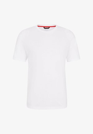 Camiseta blanca de manga corta con cuello redondo, combinada con pantalones cortos ajustados negros. Modelo con zapatillas deportivas negras. Diseño sencillo y casual.
