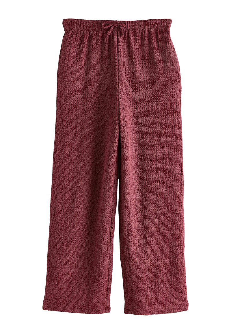 Pantalons larges en rouge bourgogne, amples, avec une taille élastique et un cordon de serrage, dotés d'un tissu texturé avec un motif de tissage subtil.