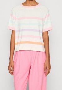 Camiseta corta de manga corta en color crema con rayas horizontales en tonos pasteles (rosa, azul, púrpura, naranja). Cuello acanalado y textura suave.