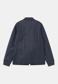 Navy quilted jacket with a ribbed collar, long sleeves, and side slits. Made of smooth, shiny fabric with vertical stitching throughout.