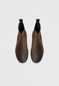 Hnědé kožené Chelsea boty s elastickými bočními panely, zaoblenou špičkou a poutkem na nazouvání. Hladká textura s jemným leskem, pevná podrážka.