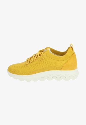 Yellow athletic shoe made of mesh and suede, featuring a rounded white sole, lace-up design, and textured accents on the upper.