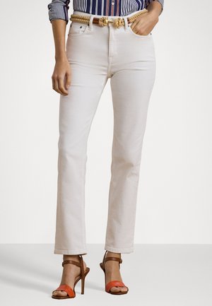 Weiße gerade Jeans aus Denim mit hoher Taille, ausgestattet mit einem geflochtenen, hellbraunen Gürtel und orangefarbenen gestreiften Sandalen. Glatte Textur und sauberes Design.