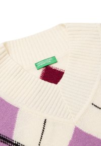 Sweter robiony na drutach w kolorze kremowym z fioletowymi i burgundowymi wzorami w romby, ściągaczowy dekolt oraz metka "United Colors of Benetton" przyszyta od wewnątrz.