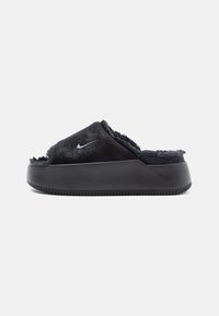 Zapatillas deslizantes negras con un forro de pelaje suave y una suela de goma texturizada, con un pequeño logo plateado de Nike en la parte superior.