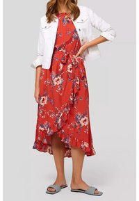 Vestido midi rojo con flores, con dobladillo con volantes y cinturón en la cintura, usado bajo una chaqueta de mezclilla blanca. Combinado con sandalias deslizantes grises.