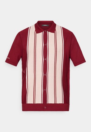 Camisa polo de manga curta, abotoada, com riscas verticais em vermelho e bege claro e um colarinho vermelho, exibida contra um fundo branco.