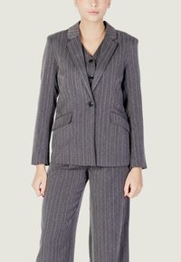 Completo grigio a righe sottili con giacca su misura e pantaloni coordinati. Presenta due tasche frontali, chiusura con un solo bottone e una texture liscia.